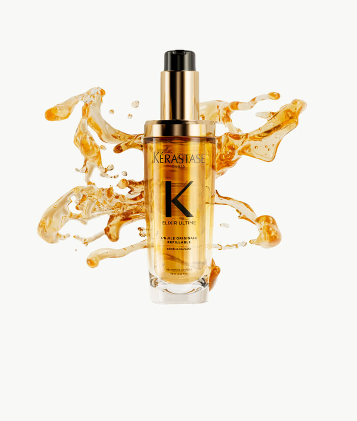Flacon de serum Kerastase Elixir Ultime, entoure de gouttes d'huile doree sur fond clair.