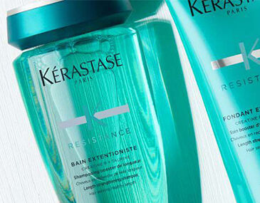 Close-up of two Kerastase hair care products: a blue shampoo bottle labeled "Bain Exextensioniste" and a conditioner tube labeled "Fondant Extentioniste," both from the Resistance line.