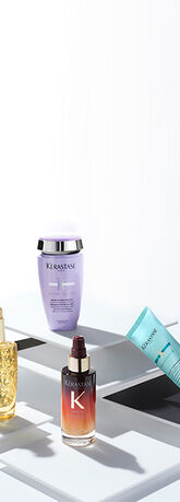 Quatre produits capillaires de la marque Kerastase presentes sur des etageres blanches, sur fond minimaliste.