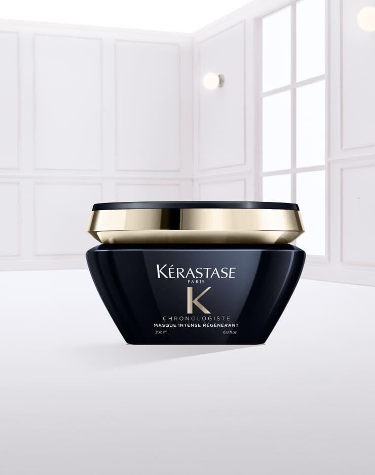 Creme capillaire Kerastase dans un pot noir, avec un couvercle dore, posee sur une surface de creme.