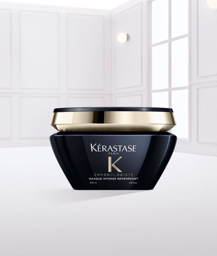 Creme capillaire Kerastase dans un pot noir, avec un couvercle dore, posee sur une surface de creme.