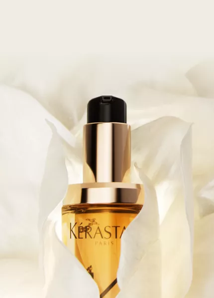 Flacon d'un serum, pose sur un petale de fleur blanche, avec un fond doux et clair.