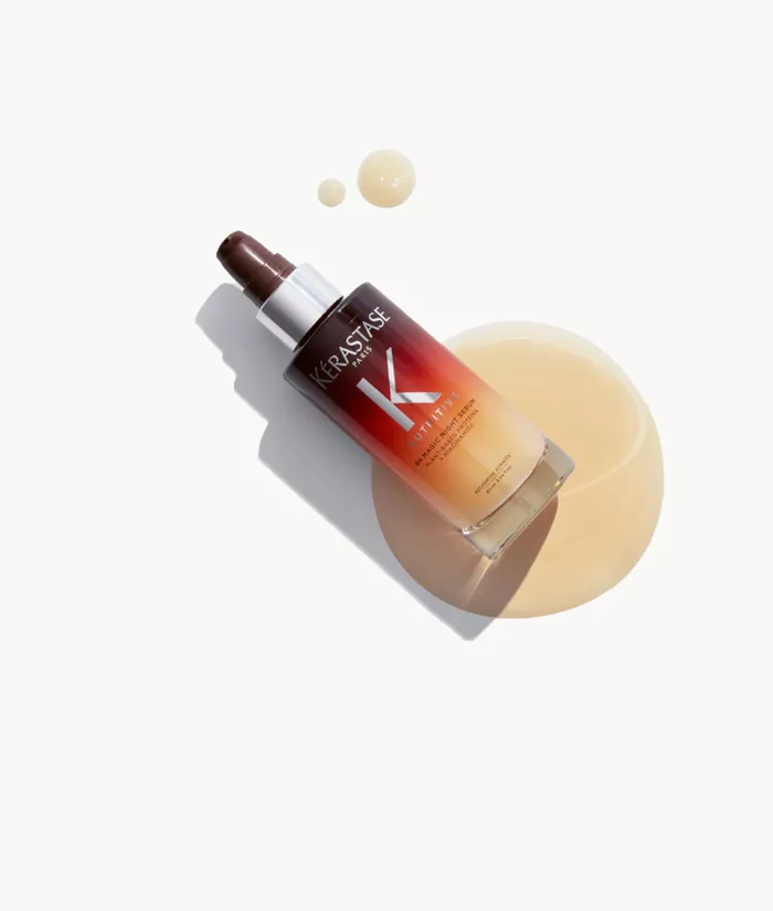Flacon de serum capillaire de la marque Kerastase, avec une texture fluide, pose sur un fond blanc.