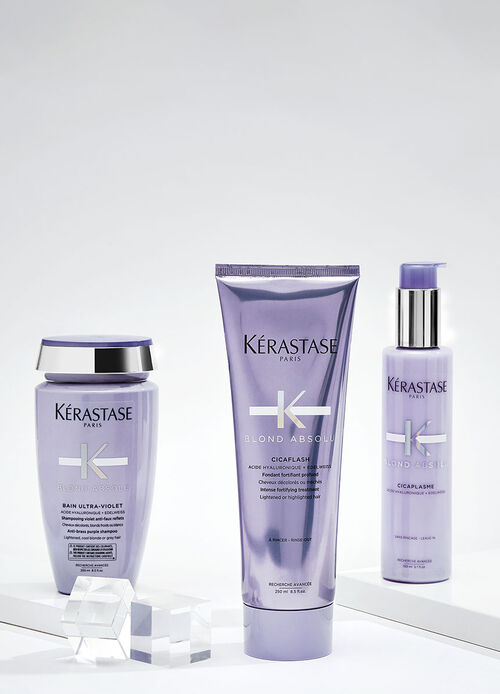 A collection of Kerastase hair care products featuring various bottles and jars, arranged artistically against a vibrant blue background.