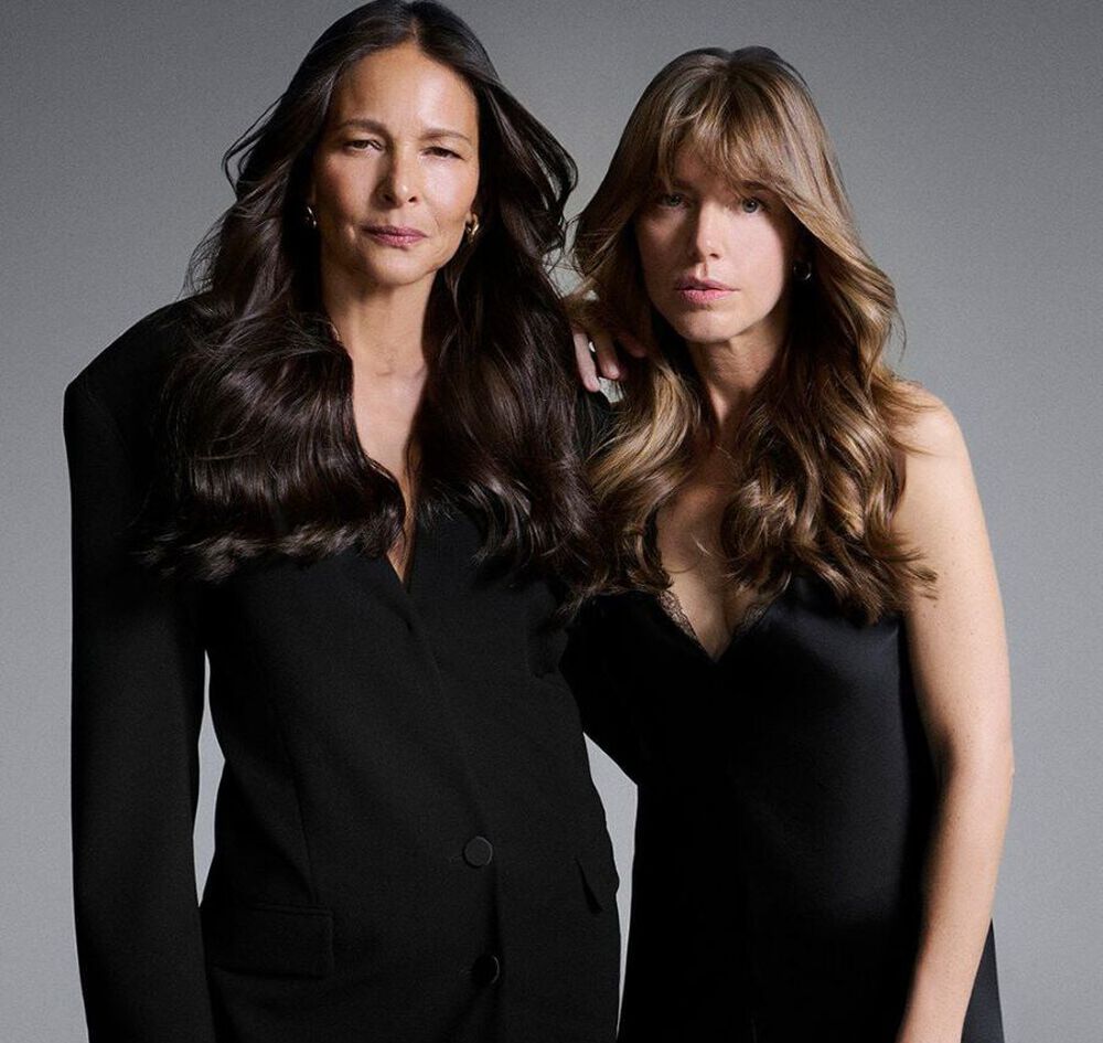 Deux femmes posant ensemble dans d'elegantes tenues noires, mettant en valeur leurs cheveux longs et sains.