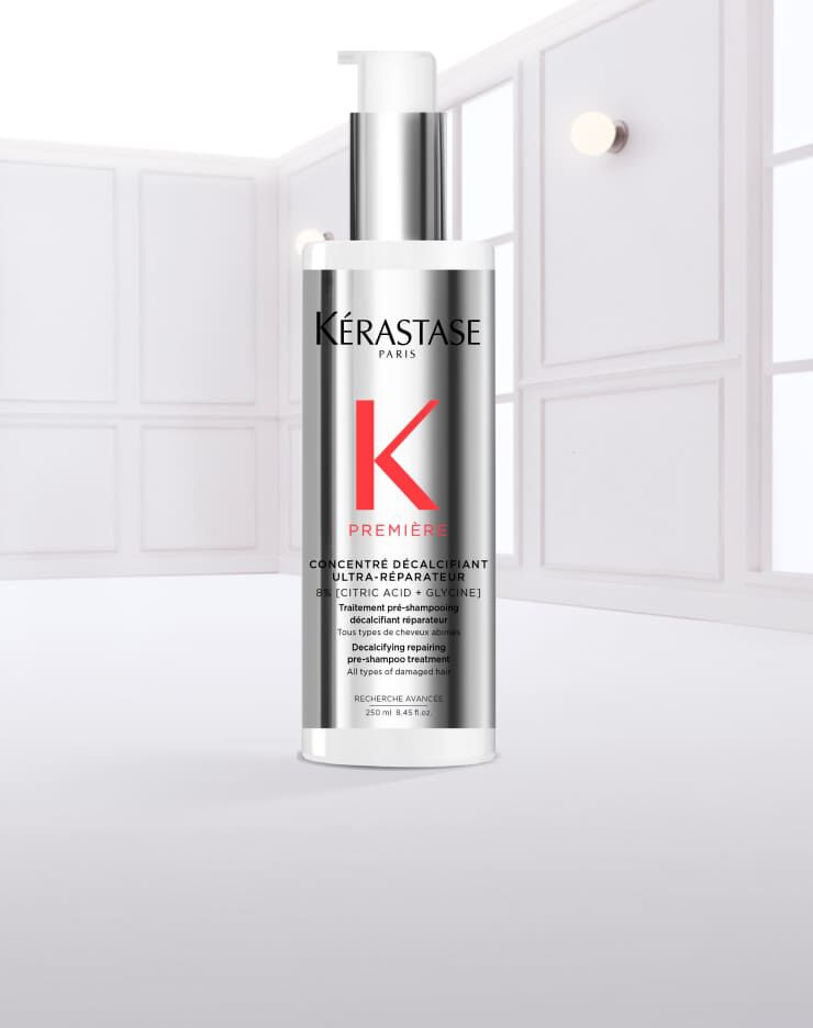 Flacon de serum capillaire Kerastase, transparent, avec des gouttes d'eau qui s'ecoulent.