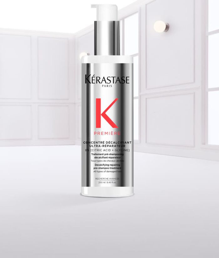 Flacon de serum capillaire Kerastase, transparent, avec des gouttes d'eau qui s'ecoulent.