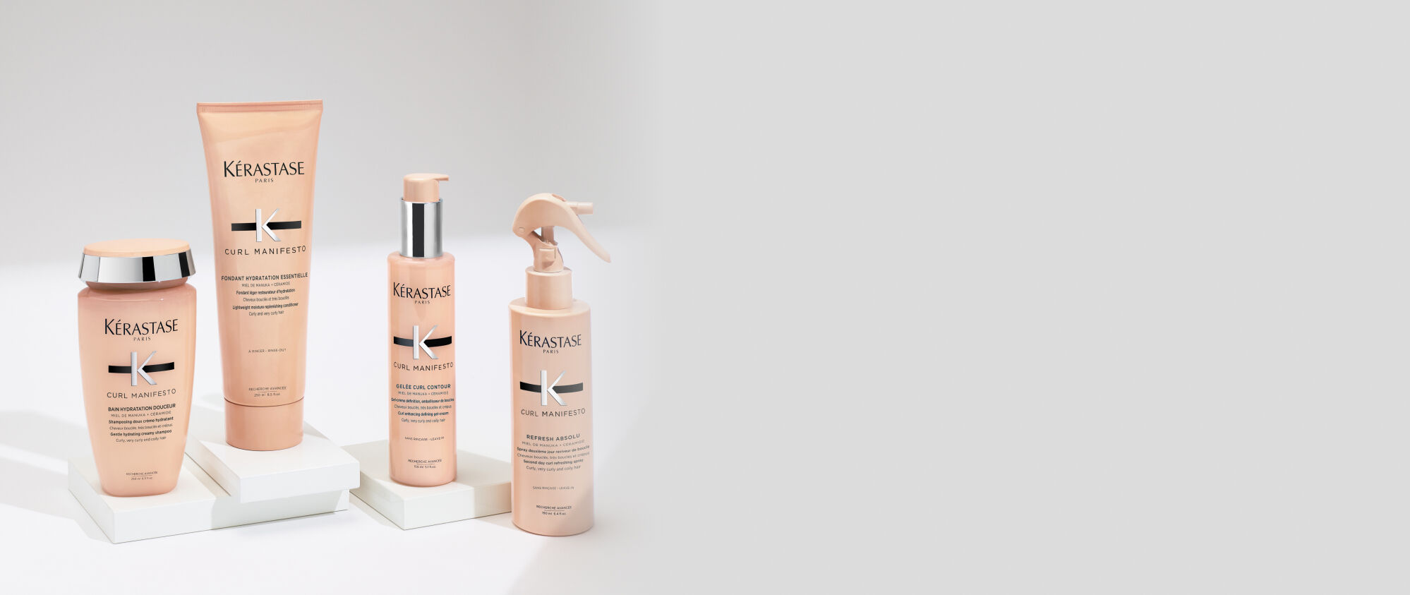 Main tenant un flacon de shampooing Kerastase Gloss Absolu avec un liquide blanc cremeux qui coule dessus.