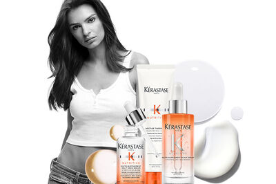 A young woman with long hair poses alongside various Kerastase haircare products, including bottles and a tube, set against a white background.