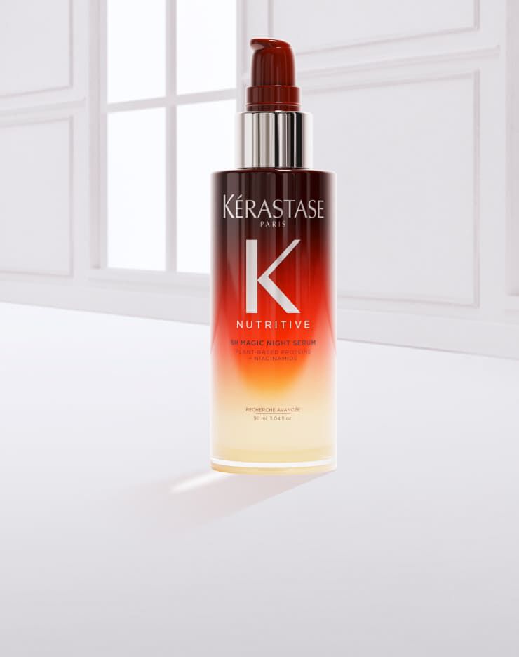 Flacon de serum capillaire de la marque Kerastase, avec une texture fluide, pose sur un fond blanc.