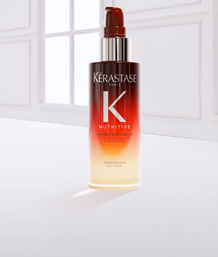 Flacon de serum capillaire de la marque Kerastase, avec une texture fluide, pose sur un fond blanc.