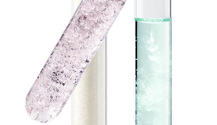 Three test tubes containing different colored liquids—one clear with bubbles, one pale pink, and one light green—set against a white background.