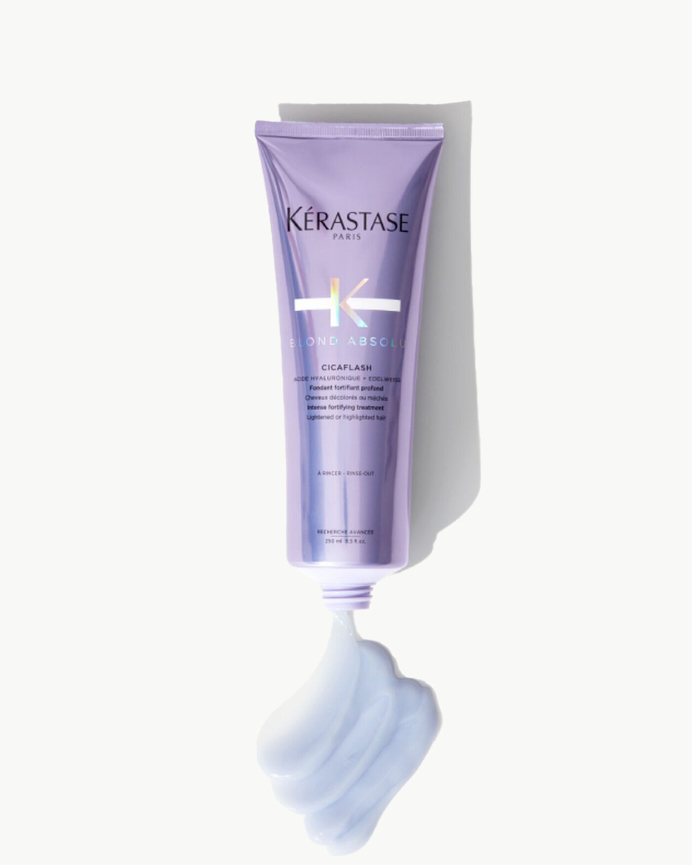 Tube de masque capillaire Kerastase Blonde Absolu Cicaplasth sur fond clair, avec une texture cremeuse en sortie du tube.