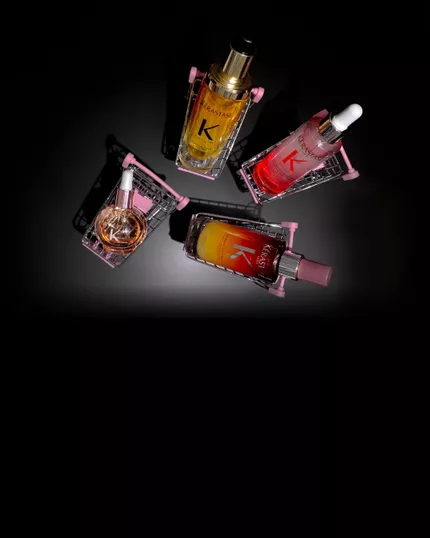 Quatre produits capillaires Kerastase dans des mini-chariots roses sur fond noir : le Serum Nuit 8H Nutritive, l'Huile Originale Elixir Ultime, le Serum Anti-chute Fortifiant de Genesis et les Glaze Drops.