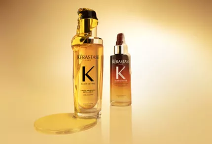Deux produits Kerastase, l'Huile Originale Elixir Ultime (flacon dore) et le Serum Nuit 8H Nutritive (flacon degrade orange), sur fond jaune dore.