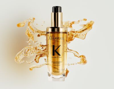 Le nouvel Elixir Ultime rechargeable est entoure de magnifiques gouttes d'huile capillaire doree et de texture.