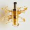 Le nouvel Elixir Ultime rechargeable est entoure de magnifiques gouttes d'huile capillaire doree et de texture.