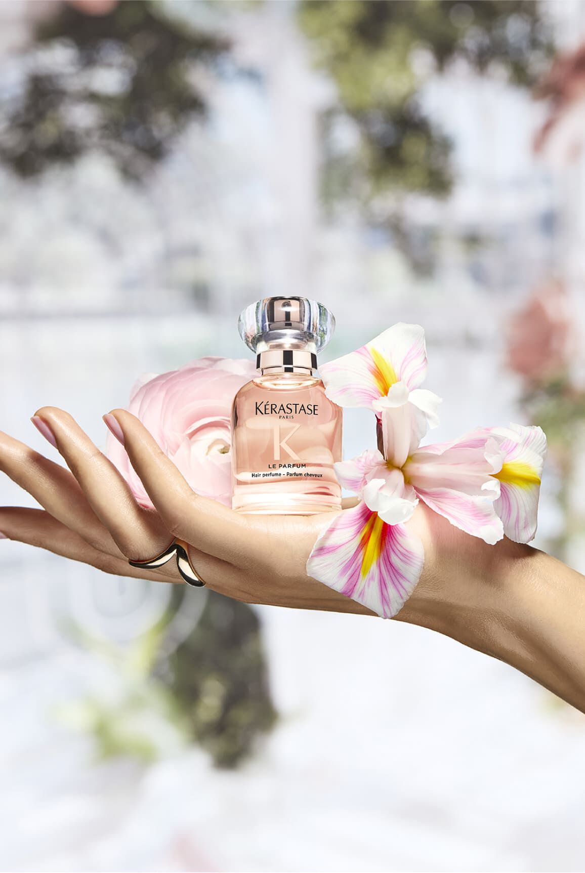 Parfum Gloss Absolu, pose sur une main dans un environnement floral qui rappelle ses ingredients​