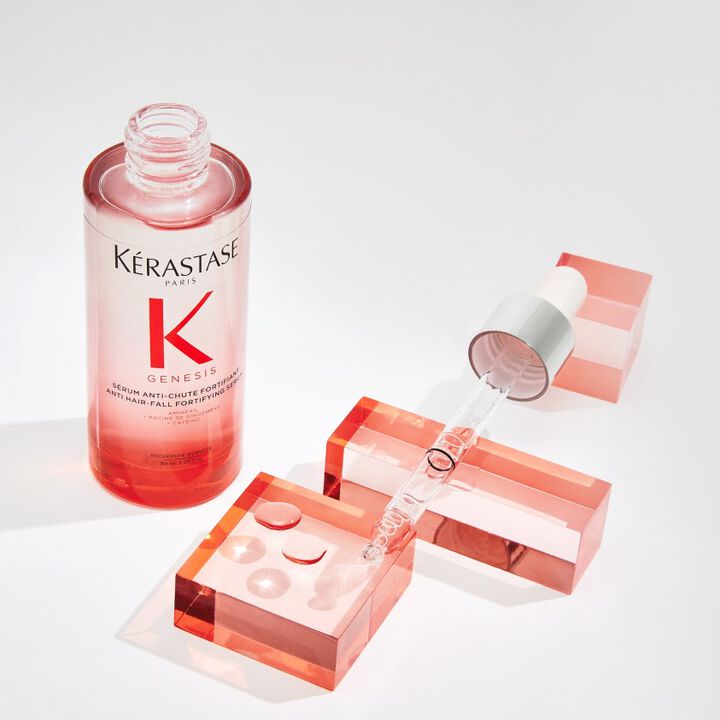 Flacon de serum anti-chute de cheveux Kerastase avec pipette, pose sur des blocs de couleur rose.