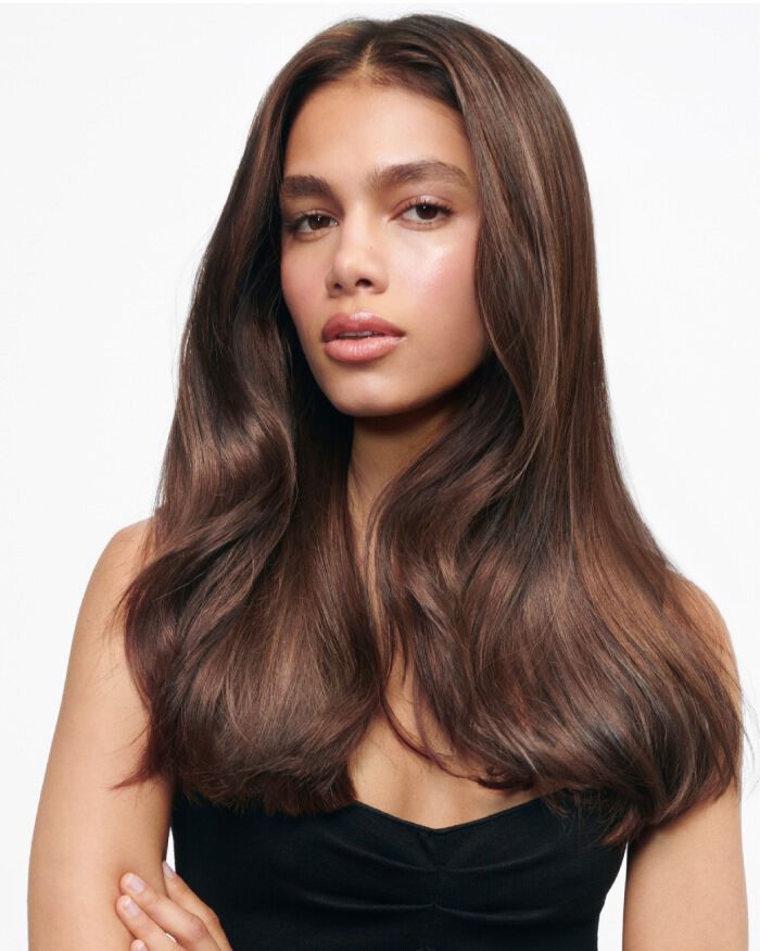 Portrait d'une jeune femme avec de longs cheveux bruns et ondules, vetue d'un haut noir, affichant une expression douce.