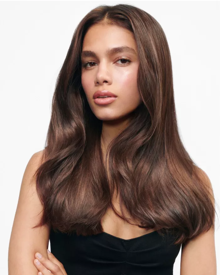 Portrait d'une jeune femme avec de longs cheveux bruns et ondules, vetue d'un haut noir, affichant une expression douce.