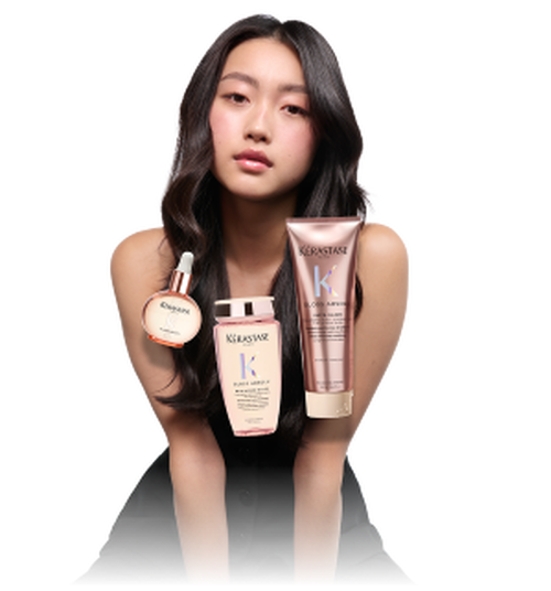 Femme avec de longs cheveux noirs, tenant des produits de soins capillaires Kerastase, dont un serum, une lotion et un masque.
