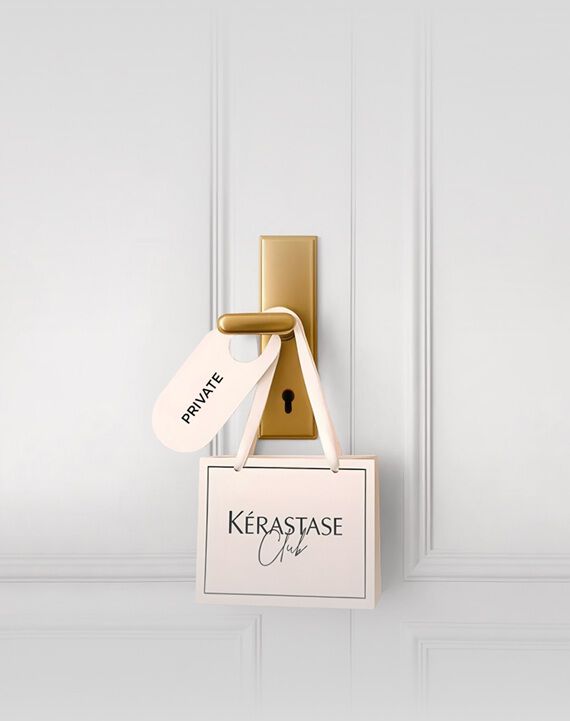 Une jeune femme aux cheveux bruns fonces, vetue d'un haut creme a decoupes et d'un pantalon clair, est allongee sur un fond gris clair, regardant directement l'objectif. Elle tient une carte de fidelite Kerastase dans sa main.