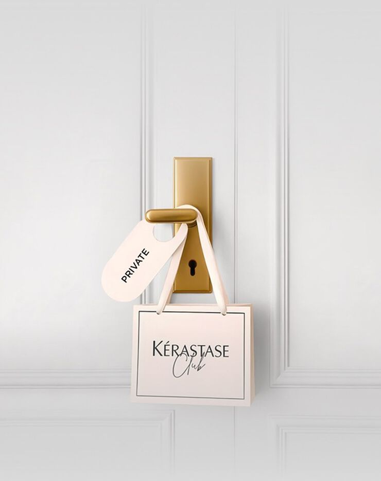 Une jeune femme aux cheveux bruns fonces, vetue d'un haut creme a decoupes et d'un pantalon clair, est allongee sur un fond gris clair, regardant directement l'objectif. Elle tient une carte de fidelite Kerastase dans sa main.