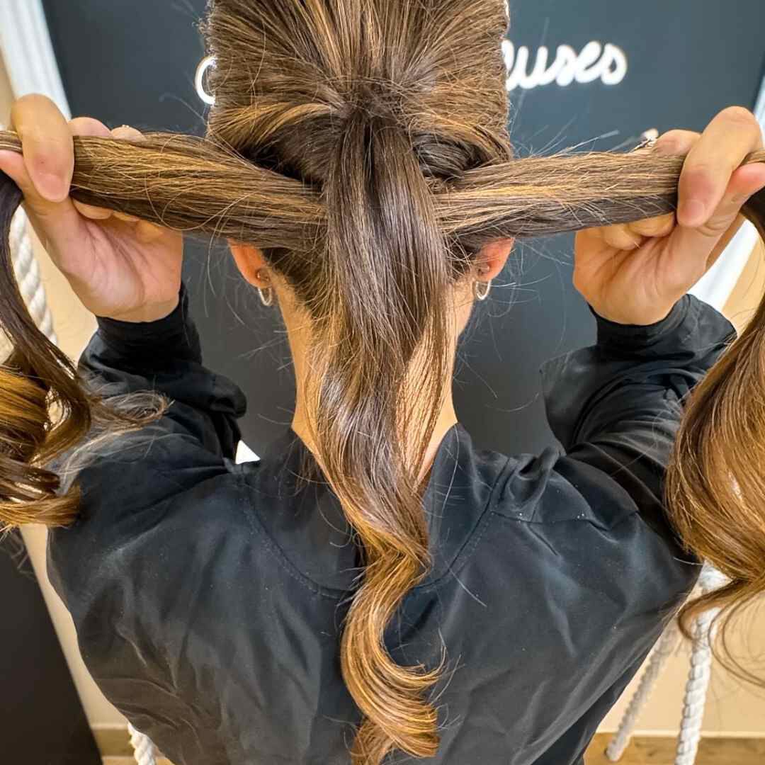 Attrapez les cheveux qui ne sont pas encore attaches et faites-les passer a l’interieur de l’attache Puis, resserrez delicatement la premiere queue  de cheval.