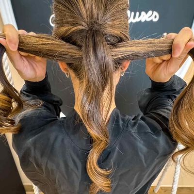 Attrapez les cheveux qui ne sont pas encore attaches et faites-les passer a l’interieur de l’attache Puis, resserrez delicatement la premiere queue de cheval.