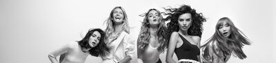 A group of five women with diverse hairstyles is posing against a plain white background. They are all facing the camera, expressing lively and playful emotions, with hair flowing dramatically. The image is in black and white.