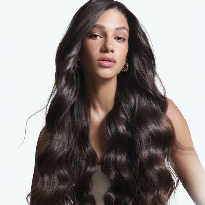 Portrait d'une femme aux longs cheveux chatain fonce, brillants et ondules.