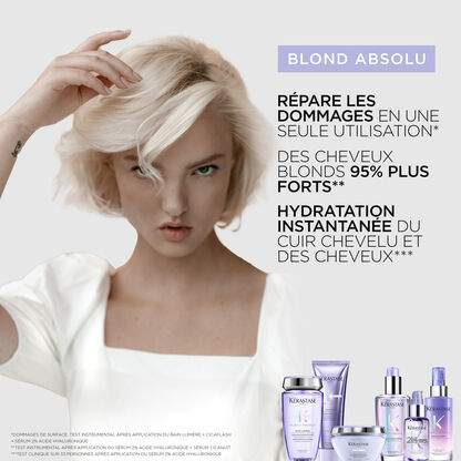 Une femme aux cheveux blonds platine presente des produits de soins capillaires Kerastase pour cheveux abimes.