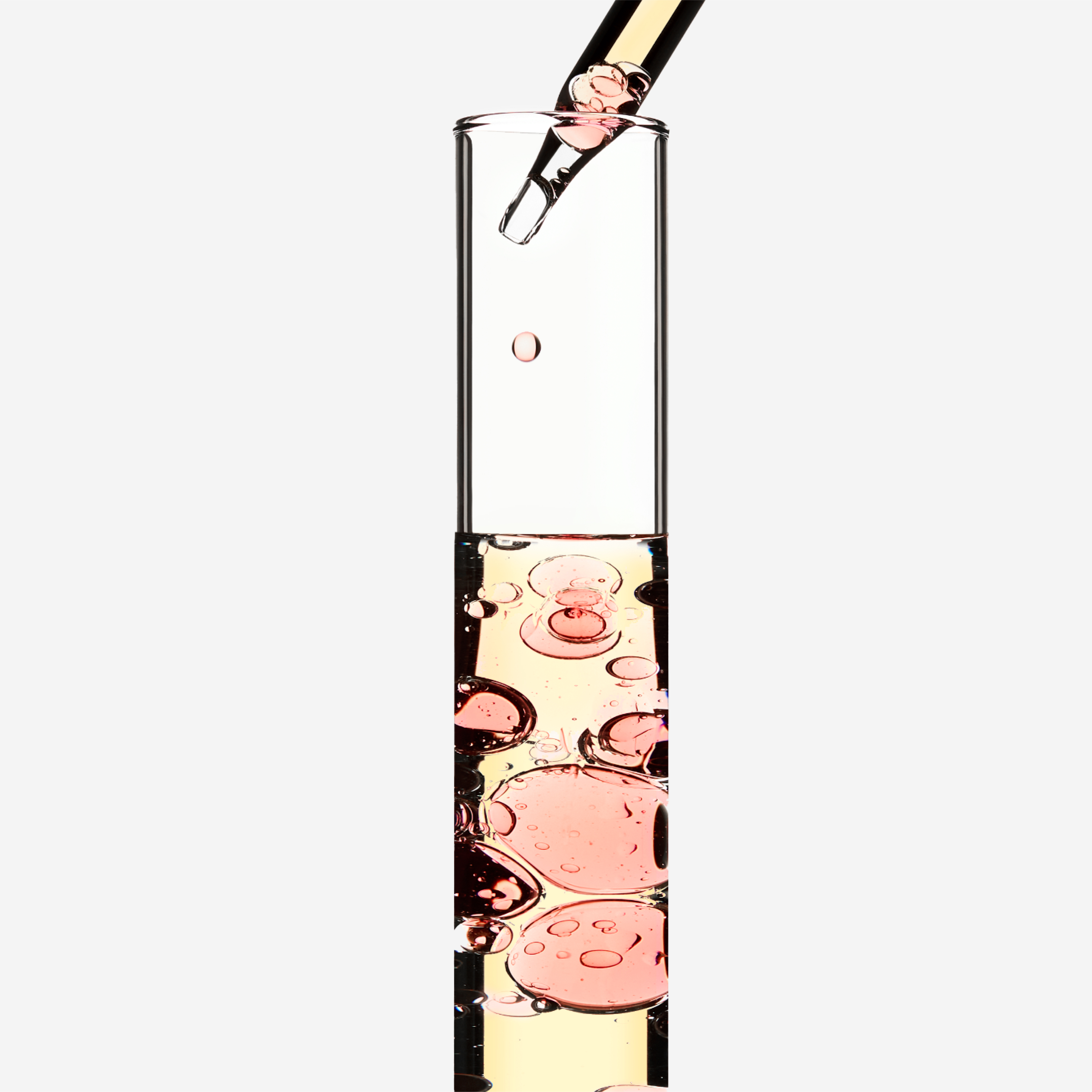 Un tube à essai rempli d'un liquide pétillant avec des bulles roses, en cours de remplissage avec une pipette.