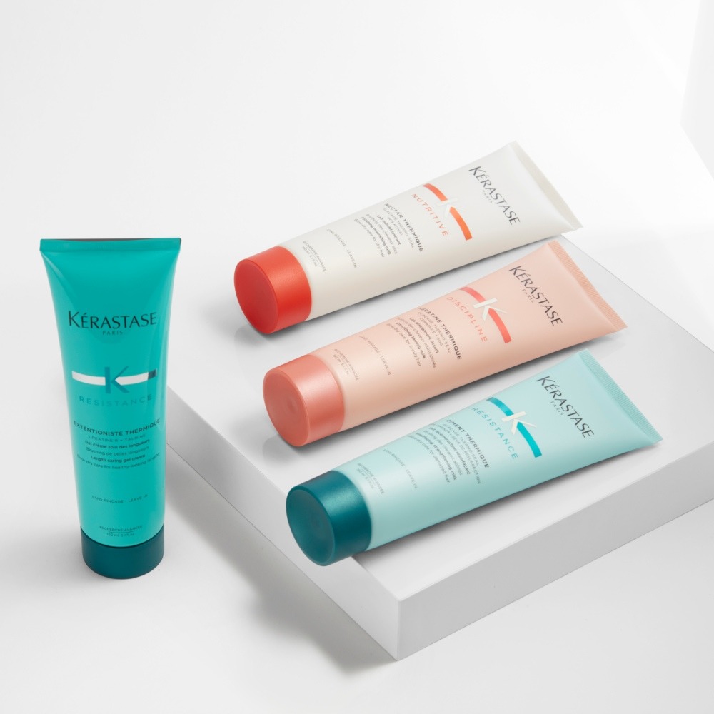 Nutritive, Discipline et Résistance Thermique de Kérastase sont présentés sur une simple plateforme grise autour d'un fond gris pur.