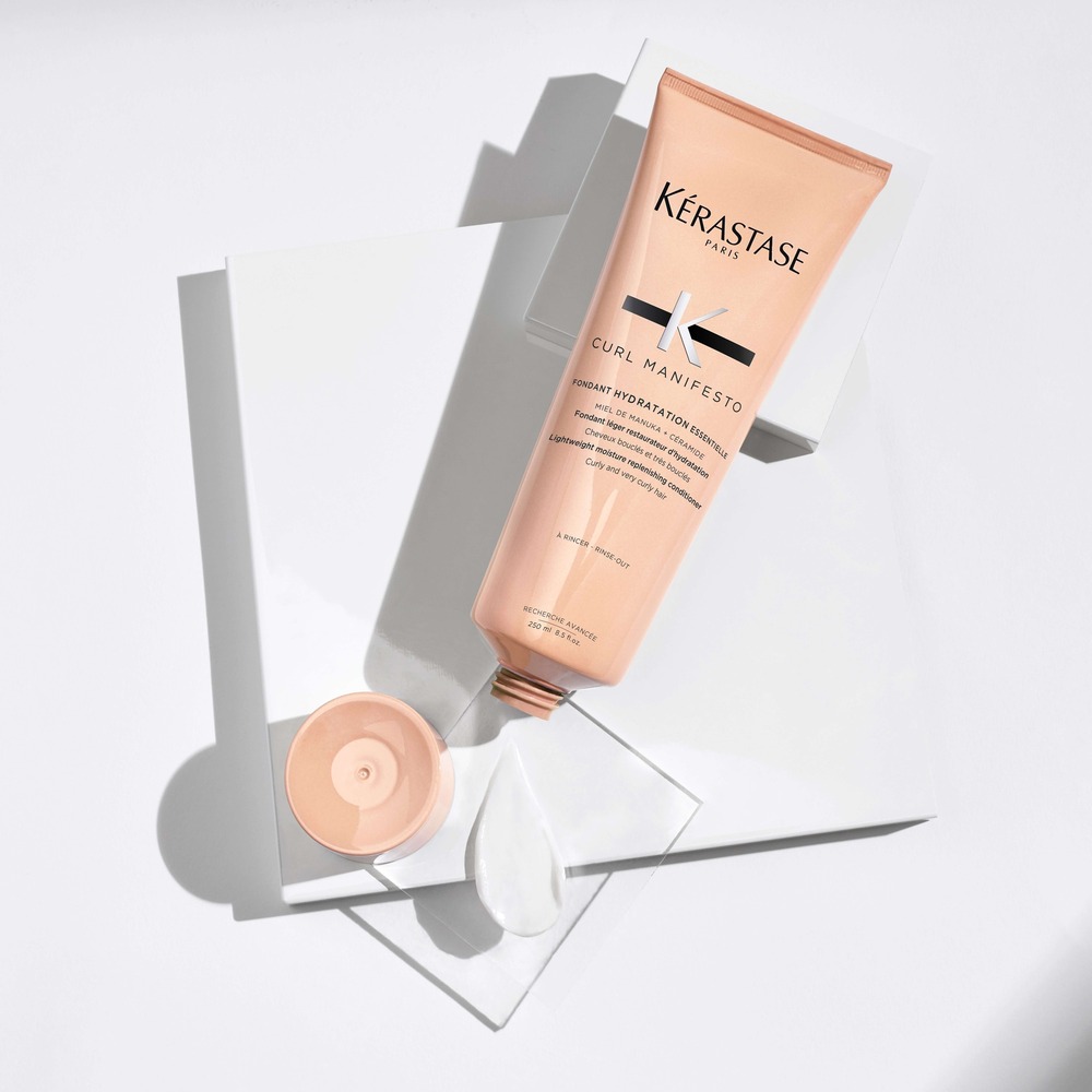 Crème hydratante Kérastase Curl Manifesto sur une surface blanche, prête à être utilisée pour les cheveux bouclés.
